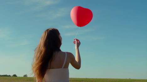 a person releases a red balloon into the sky