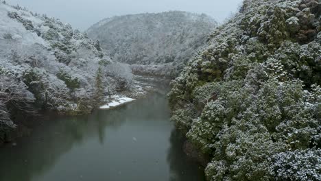 snow falling over katsura river, kyoto japan