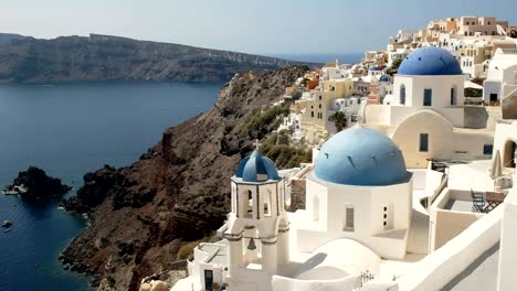 panning shot of the famous three blue domes at oia, santorini