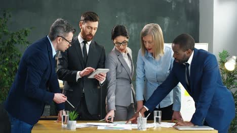 multiethnische gruppe von geschäftsleuten und büroangestellten um einen tisch mit dokumenten und besprechung neuer projekte im büro