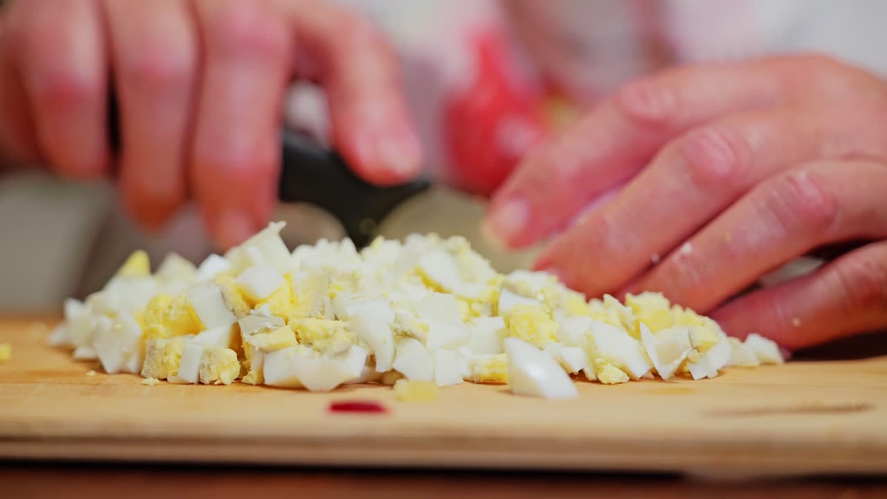 Chopped egg cubes prepped on board during family cooking session at home - 4K