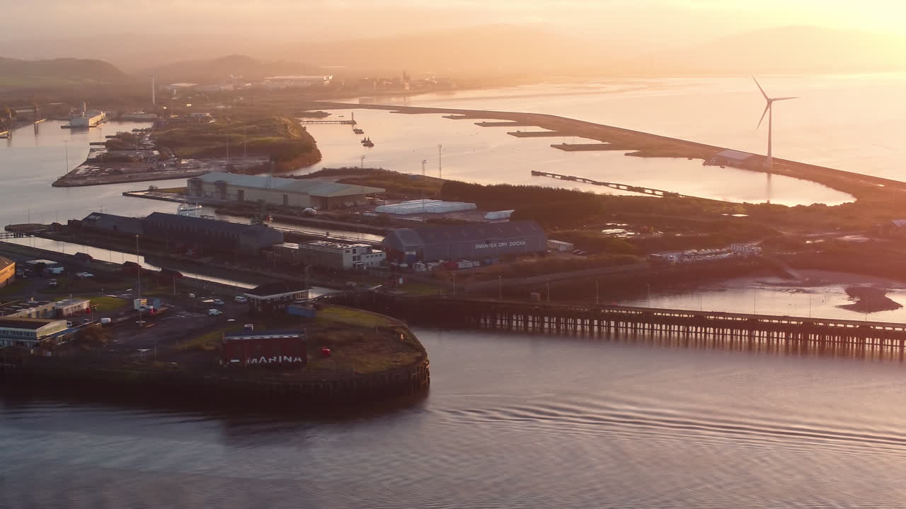Aerial of Queen's Dock in Swansea Marina with Wind Turbine Rotating at Sunrise. Maritime Industrial Port Landscape for Docking Transported Cargo and Boat Repair and Maintenance