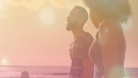 Animation-of-light-spots-over-african-american-couple-walking-at-beach