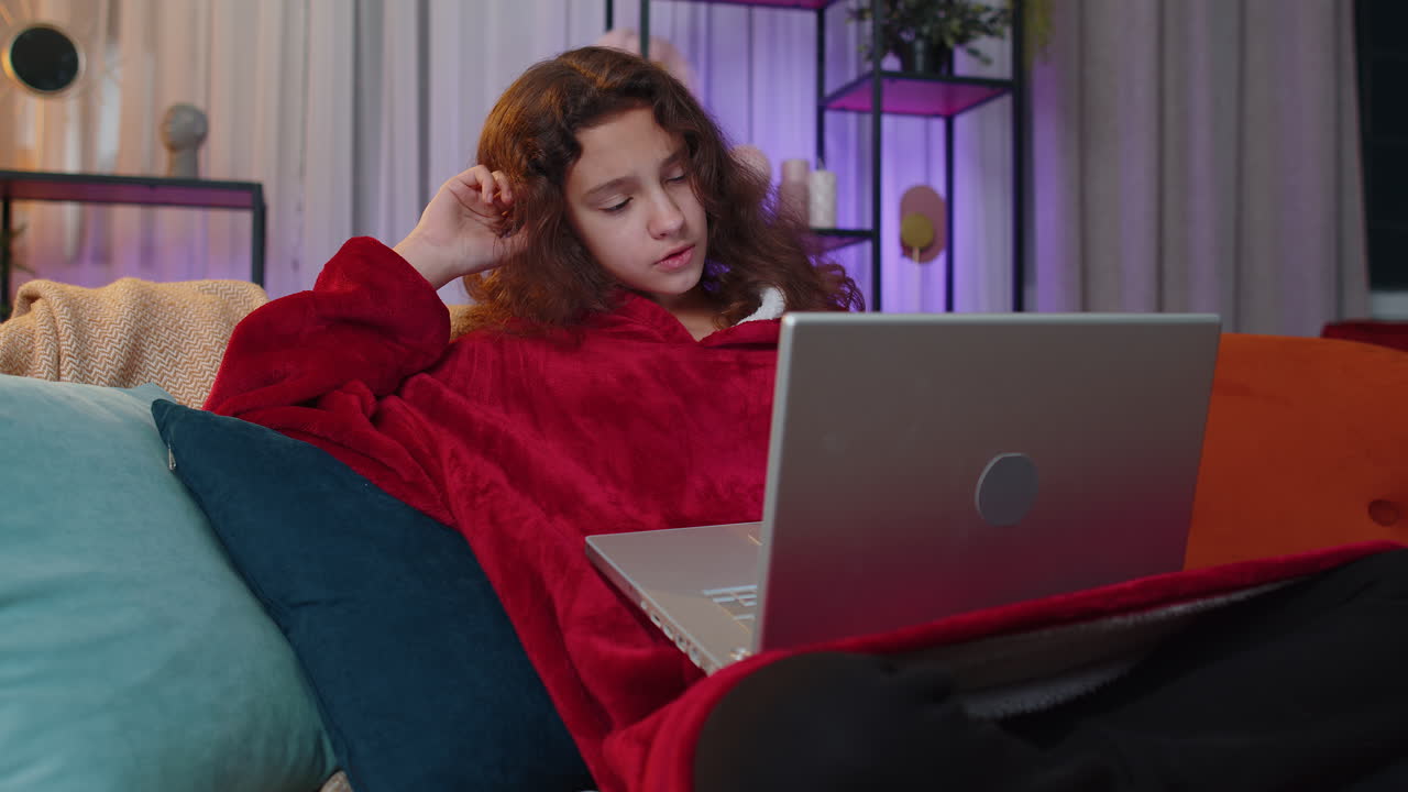chica sentada en el sofá de casa, mirando a la cámara, haciendo una llamada de videoconferencia con amigos o familiares