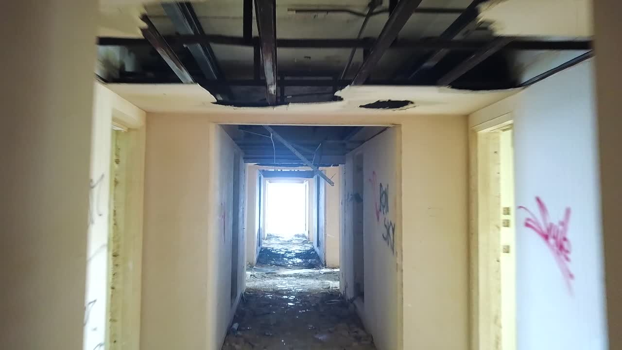 Drone flying through a scary hallway of an abandoned hotel in Malta. Destroyed building. Light at the end of the tunnel.