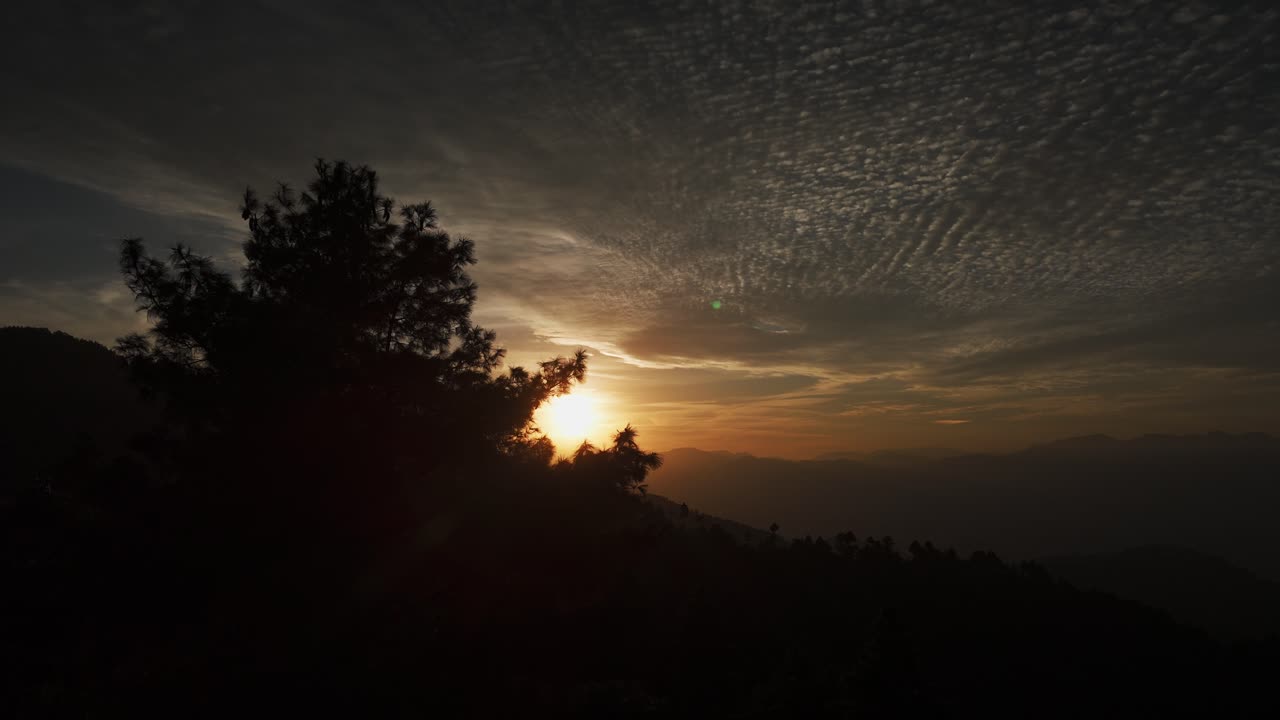 Nádherný západ slunce osvětluje oblaka altocumulus teplými odstíny a jemnými texturami. Mraky ve střední výšce dodávají hloubku a atmosféru a vytvářejí klidnou a malebnou večerní oblohu.