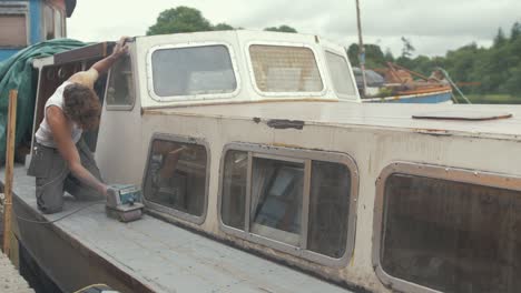 Joven-Trabajando-En-Topless-En-Verano-Sellando-El-Techo-De-La-Cabina-Del-Barco-De-Madera-Para-Evitar-Fugas