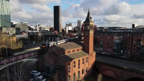 aerial drone flight over deansgate railway station in manchester city centre showing a train passing by over a bridge and pulling into the station