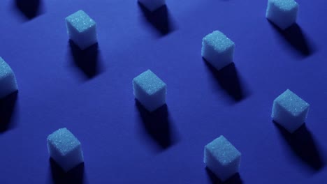 A-4K-tilt-up-view-of-a-unique-cubic-background-with-white-sugar-cubes-symmetrically-arranged-in-rows-on-a-dark-blue-background,-3D-effect