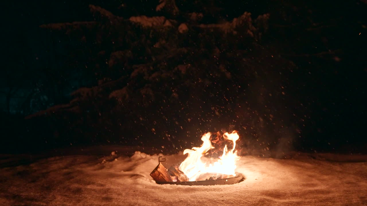 눈이 내리는 동안 밤에는 뜨거운 춤추는 불꽃이 불타는 것처럼 눈에 나무를 습니다.