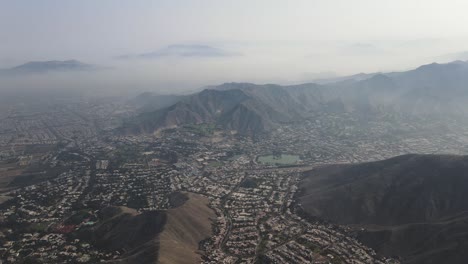 a misty drone shot of a lagoon and hills of the city of lima