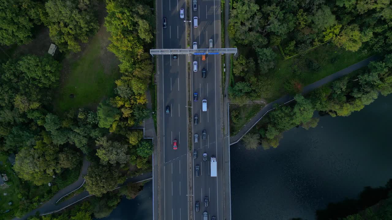 busy highway traffic crossing a bridge over a river surrounded by trees. Perfect aerial view flight drone camera pointing down