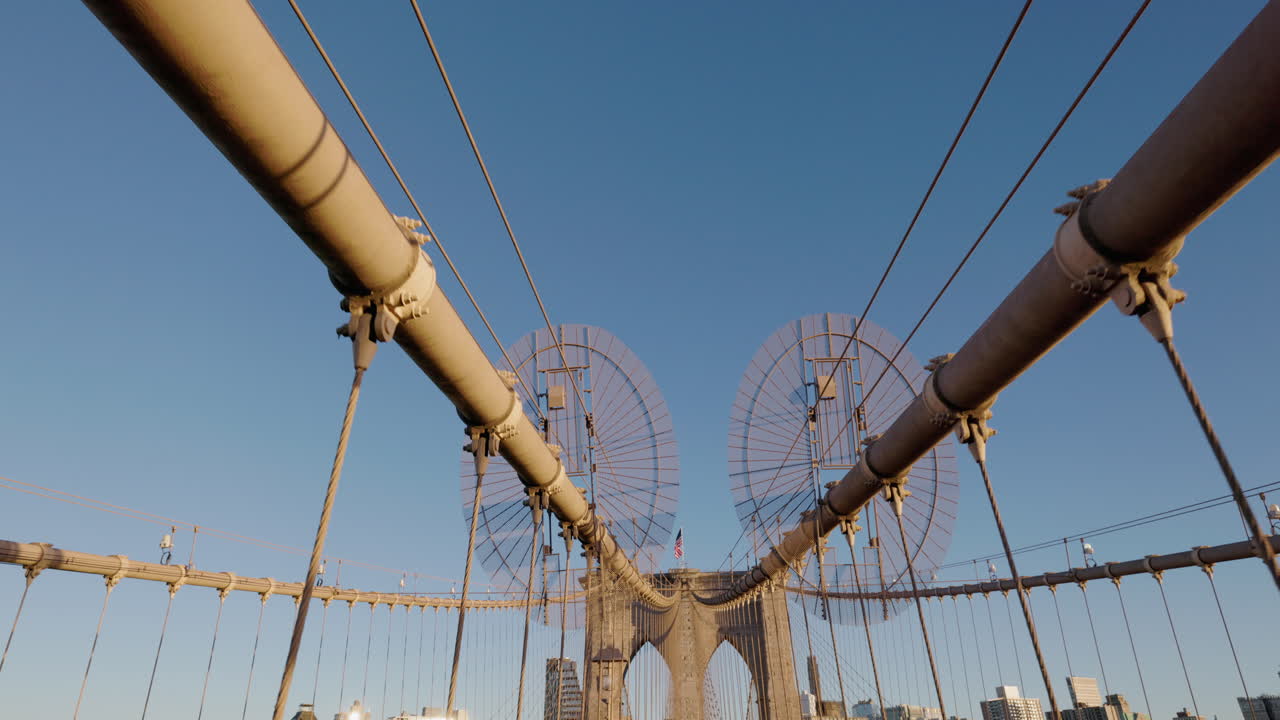 Brooklyn Bridge upper cables and walkway perspective under clear blue sky in New York City