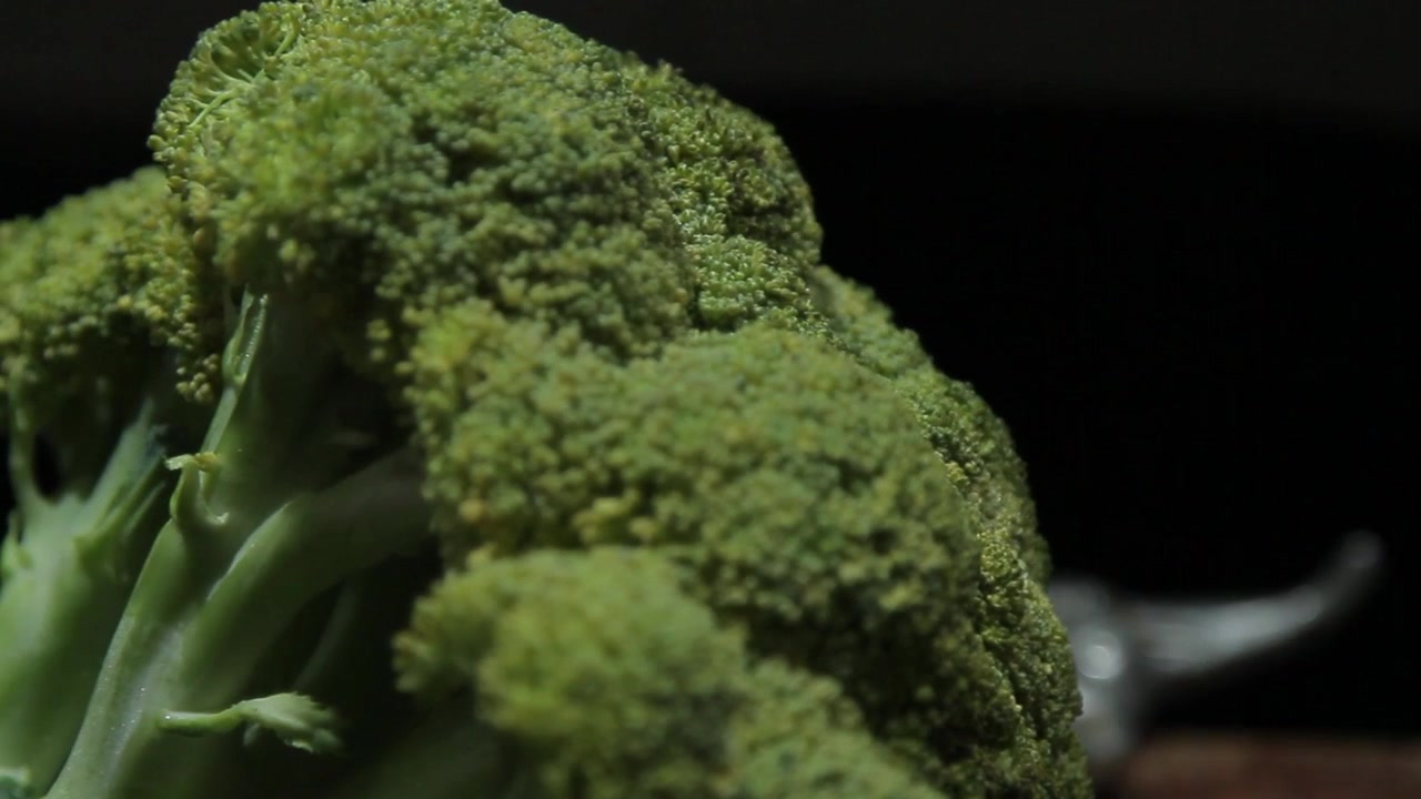 Ripresa panoramica a sinistra con passaggio di messa a fuoco dalla testa di mucca ai broccoli freschi e verdi, a simboleggiare la dieta vegetariana