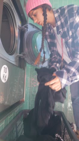 adolescente haciendo la ropa en una lavandería automática