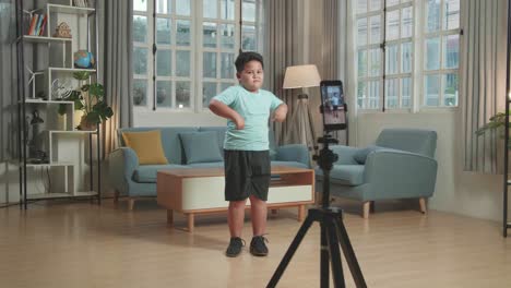 asian little boy dancing while shooting video content for social networks with a smartphone camera