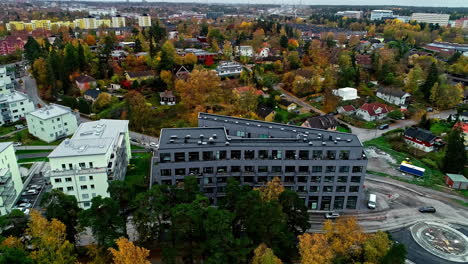 drone aéreo giratorio disparado sobre edificios residenciales a lo largo del suburbio de estocolmo rodeado de árboles de otoño en suecia durante el día