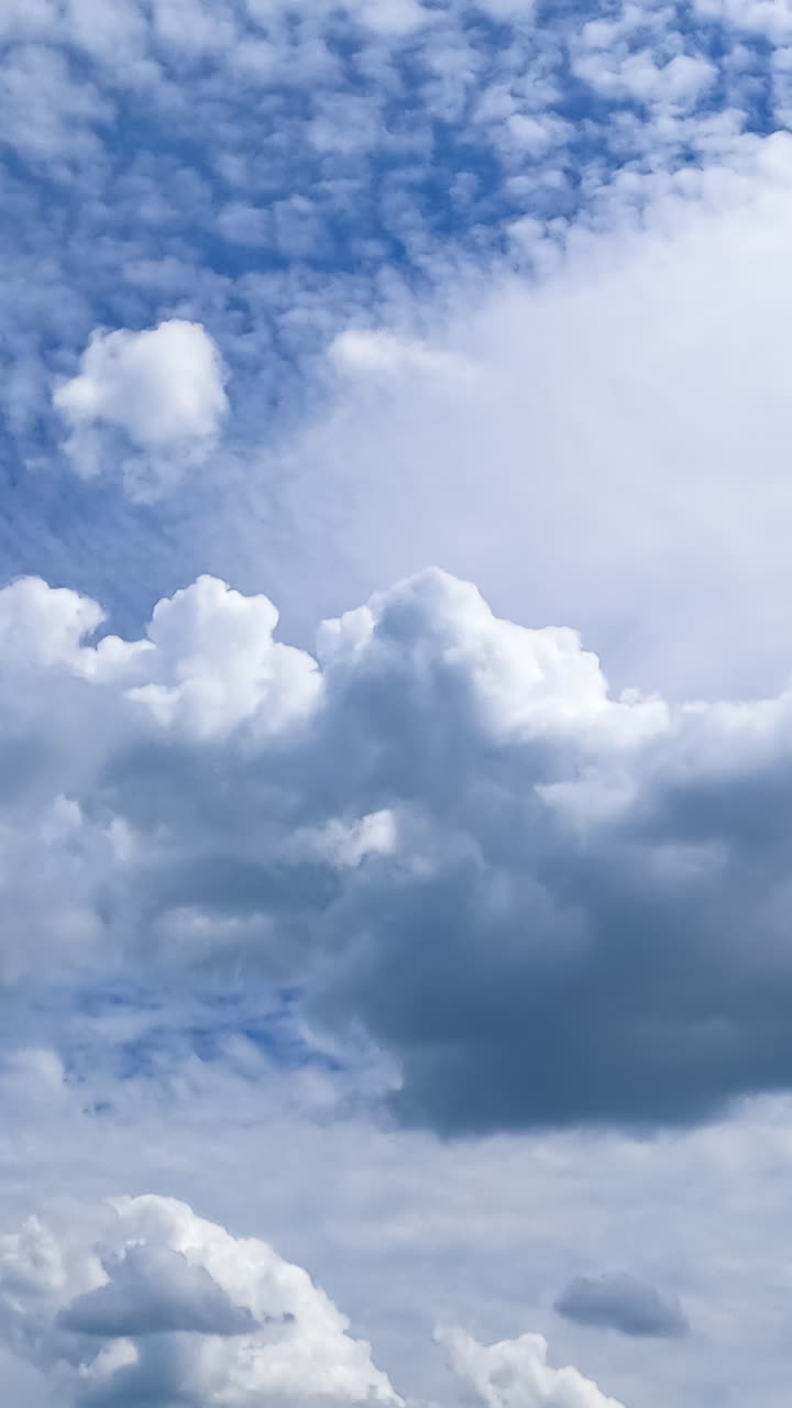 Beautiful cloudscape transformation in the sky. Cumulus and spindrift types of clouds moving on sunny daytime. Timelapse. Vertical video