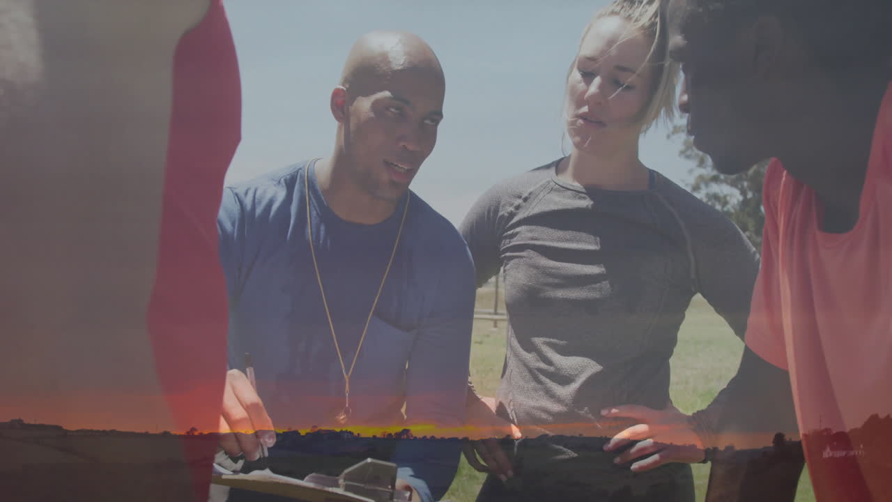 Discussing strategy outdoors, diverse athletes with animation overlay at sunset