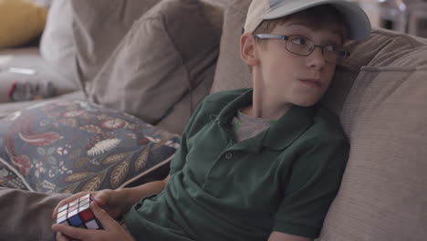 boy sitting on a couch plays with a cube puzzle game