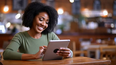 Smiling Woman Using a Tablet in a Cafe