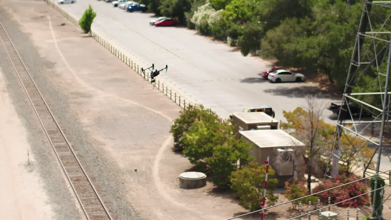 avión no tripulado volando más allá de la zona industrial, ferrocarril y líneas eléctricas