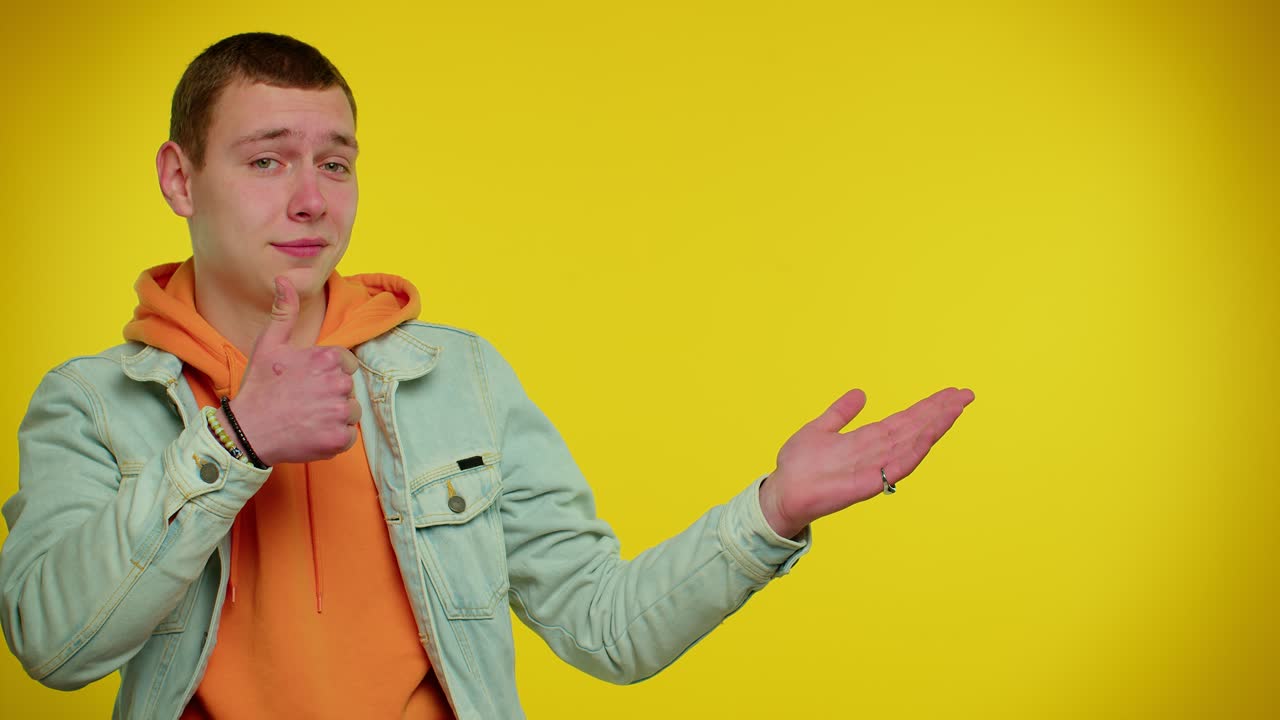 젊은이가 웃으며 한 손을 으로 가리키며 엄지손가락을 니다.