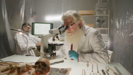 Senior Scientist Observing Sample through Microscope in Archaeology Lab