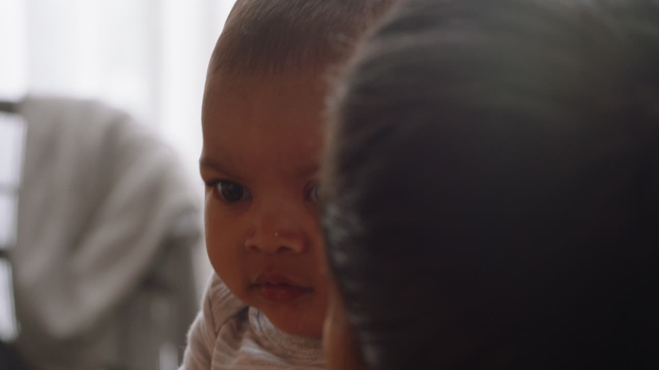 초상화 행복한 아기가 웃고 호기심 많은 아기가 관심을 받고 젊은 어머니가 집에서 아이를 안고 있습니다.