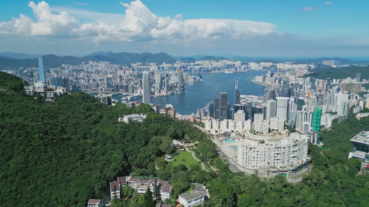 Aerial drone footage capturing Victoria Peak and Hong Kong Harbour, showcasing panoramic city skyline, waterfront, and coastal scenery, highlighting urban architecture and iconic landmarks from above