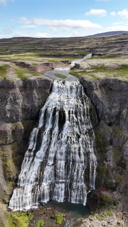 aerial view flying towards the breathtaking hrisvaosfoss waterfall in iceland, vertical video wide panning shot.