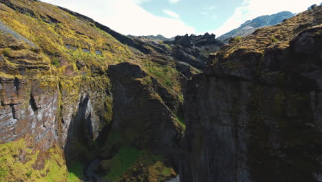 The-aerial-reveal-of-mountain-peaks-above-cliffs-of-a-rocky-ravine