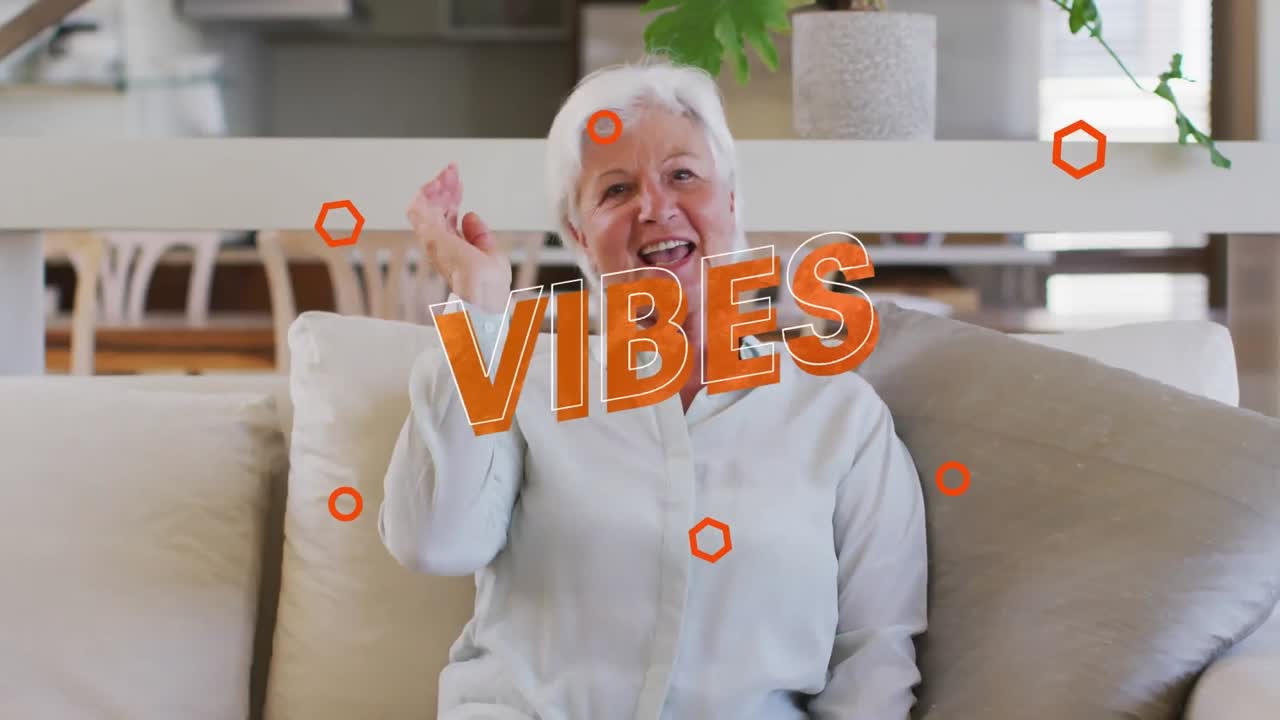 Animation of vibes text in orange over happy caucasian woman making video call at home