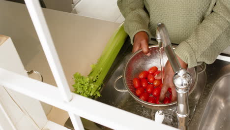 Hände-Einer-Afroamerikanischen-Seniorin,-Die-Tomaten-In-Einer-Sonnigen-Küche-Wäscht,-Zeitlupe