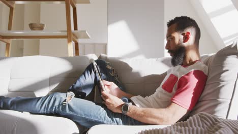 handsome man using digital tablet while relaxing on the couch