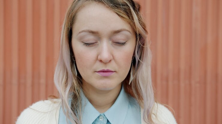 Woman with Closed Eyes in Front of Orange Wall