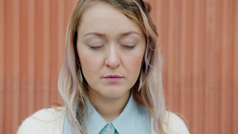 woman with closed eyes in front of orange wall