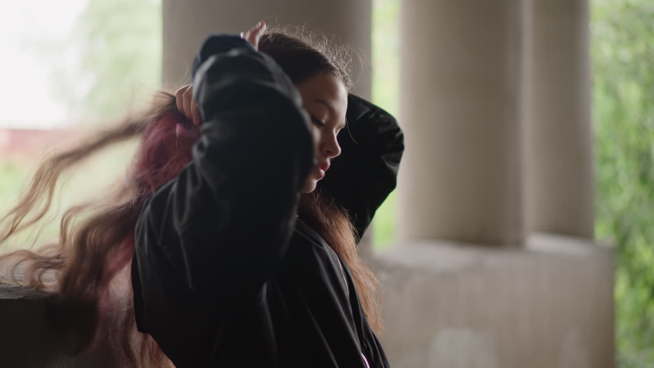 Scena piovosa con una donna sotto un cavalcavia, caratterizzata da luce soffusa e riflessi. Una figura femminile contemplativa si sistema i capelli sotto il cavalcavia, con riflessi realistici e un'atmosfera cinematografica.