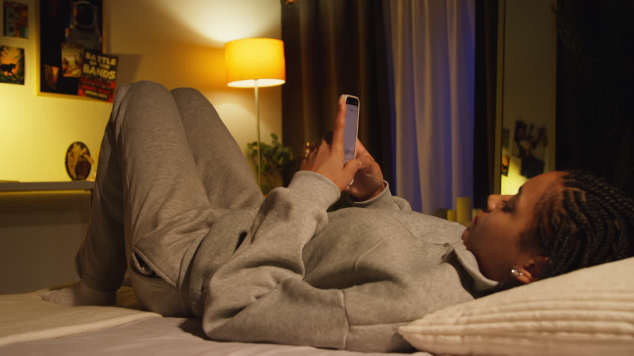 Adolescente che usa il telefono a letto di notte