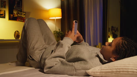 teenager using phone in bed at night