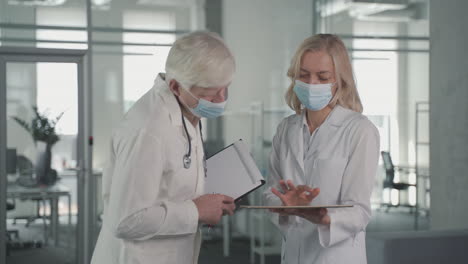 a pair of doctors with masks converse while looking at results on a tablet