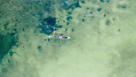 aerial top down drone shot of a phishing boat on clear water in zanzibar, tanzania