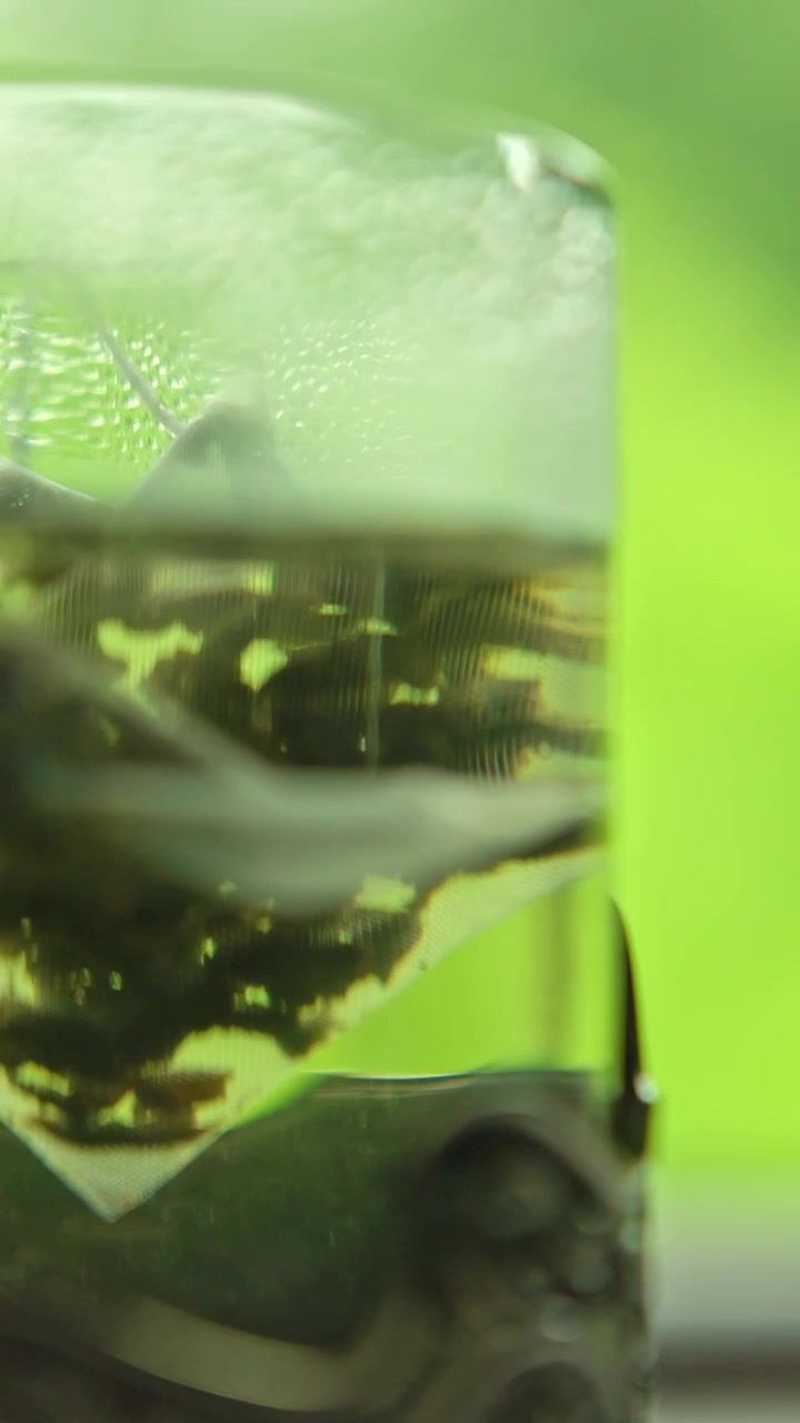 Close-up of Tea Leaves Steeping in Hot Water in a Glass Cup