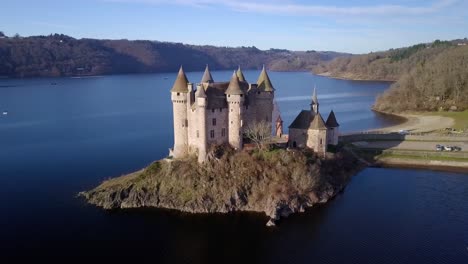 un avión no tripulado filmado alrededor de chateau de val, castillo francés en la orilla del lago artificial de bort les orgues en un día soleado durante el invierno, departamento de cantal, auvergne, región de ródano alpes, francia