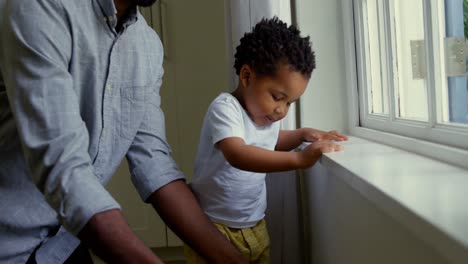 Mid-section-of-young-black-father-playing-with-his-son-on-window-sill-in-a-comfortable-home-4k