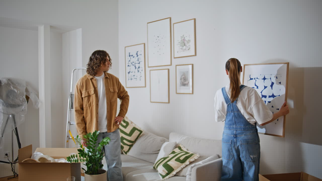 wife holding artwork while decorating new home. Happy woman styling