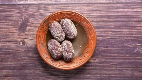 hand reaching for indian sweets on a plate