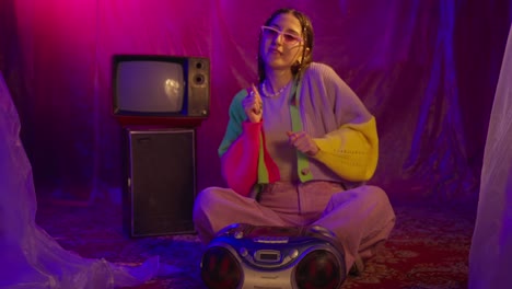 young woman dancing to retro music with a boombox in a neon-lit setting