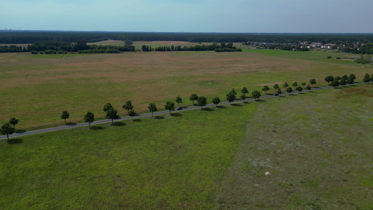 coches conduciendo en una carretera de campo cruzando vastos campos bajo un cielo azul. espectacular vista aérea vuelo panorámica de órbita amplia drone