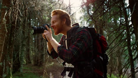 tourist shooting green landscape in forest. photographer using photo camera